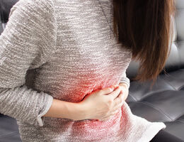 A woman holds both hands to her stomach as though she feels sick.