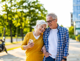 A man and woman walk down a street arm-in-arm.